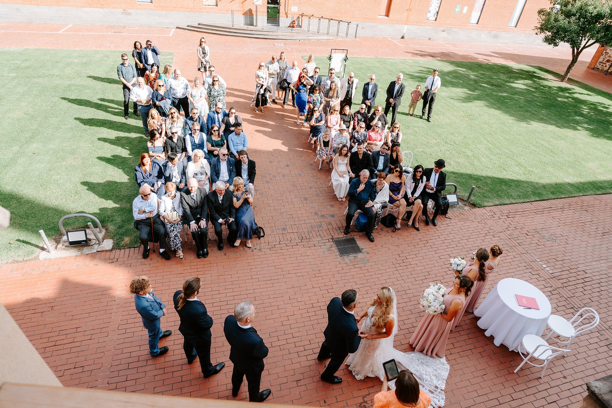 Looking down from the staircase over the ceremony, guests on both sides of the brick aisle.
