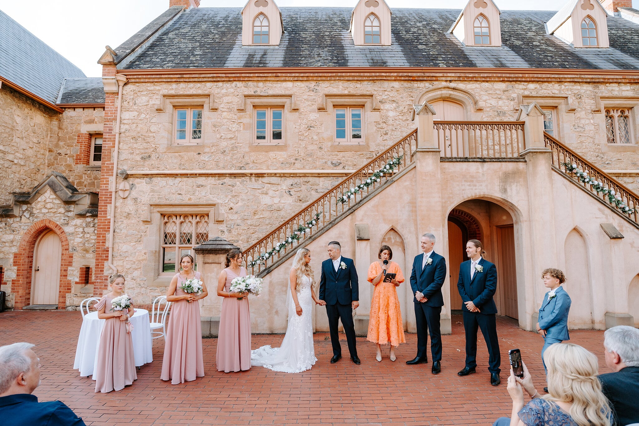 Sarah and Joe stand with their bridesmaids and groomsmen in front of the Armoury’s twin staircase.