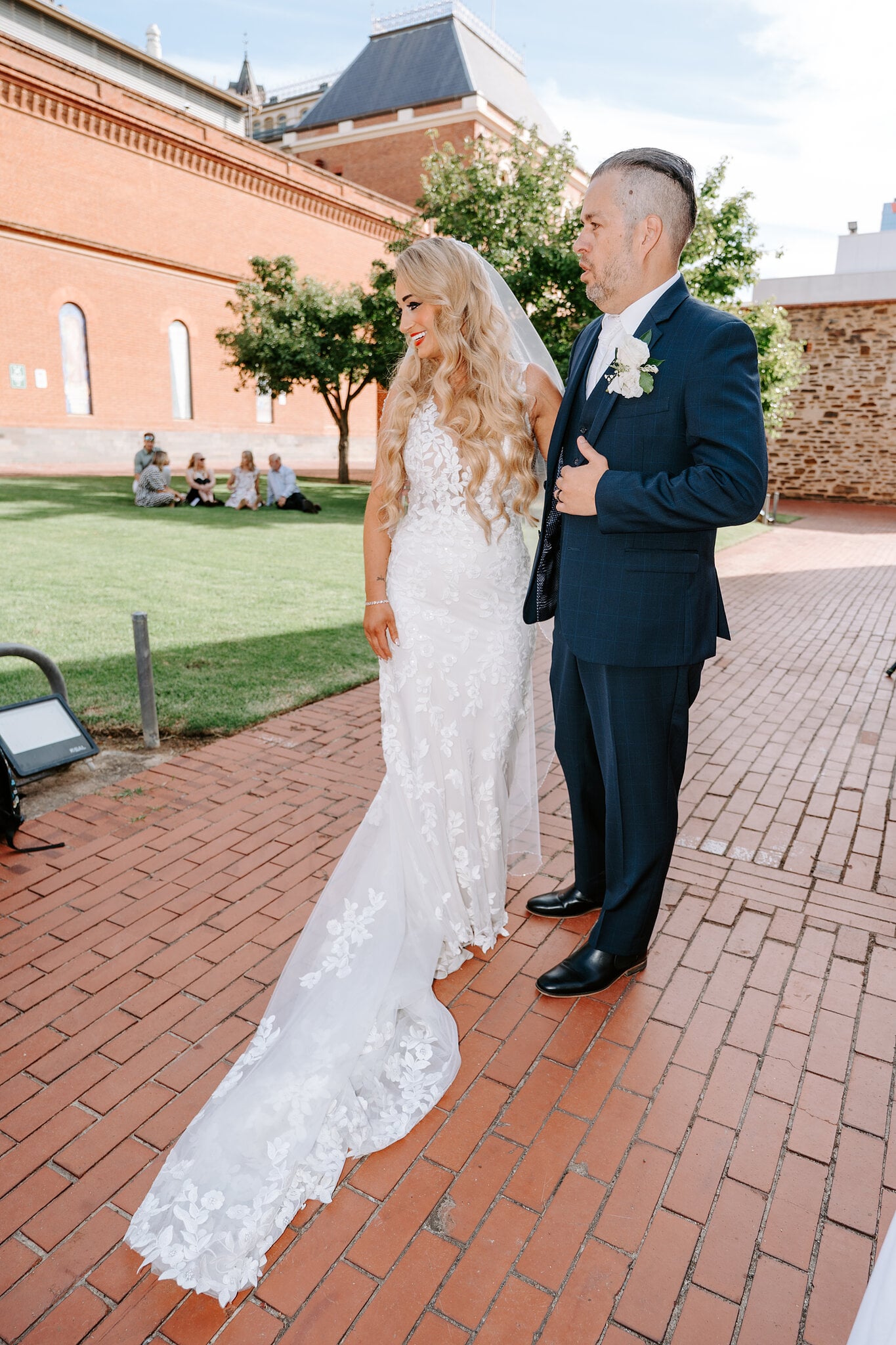 Sarah and Joe stand side by side on the brick path, the museum’s red-brick wing behind them.