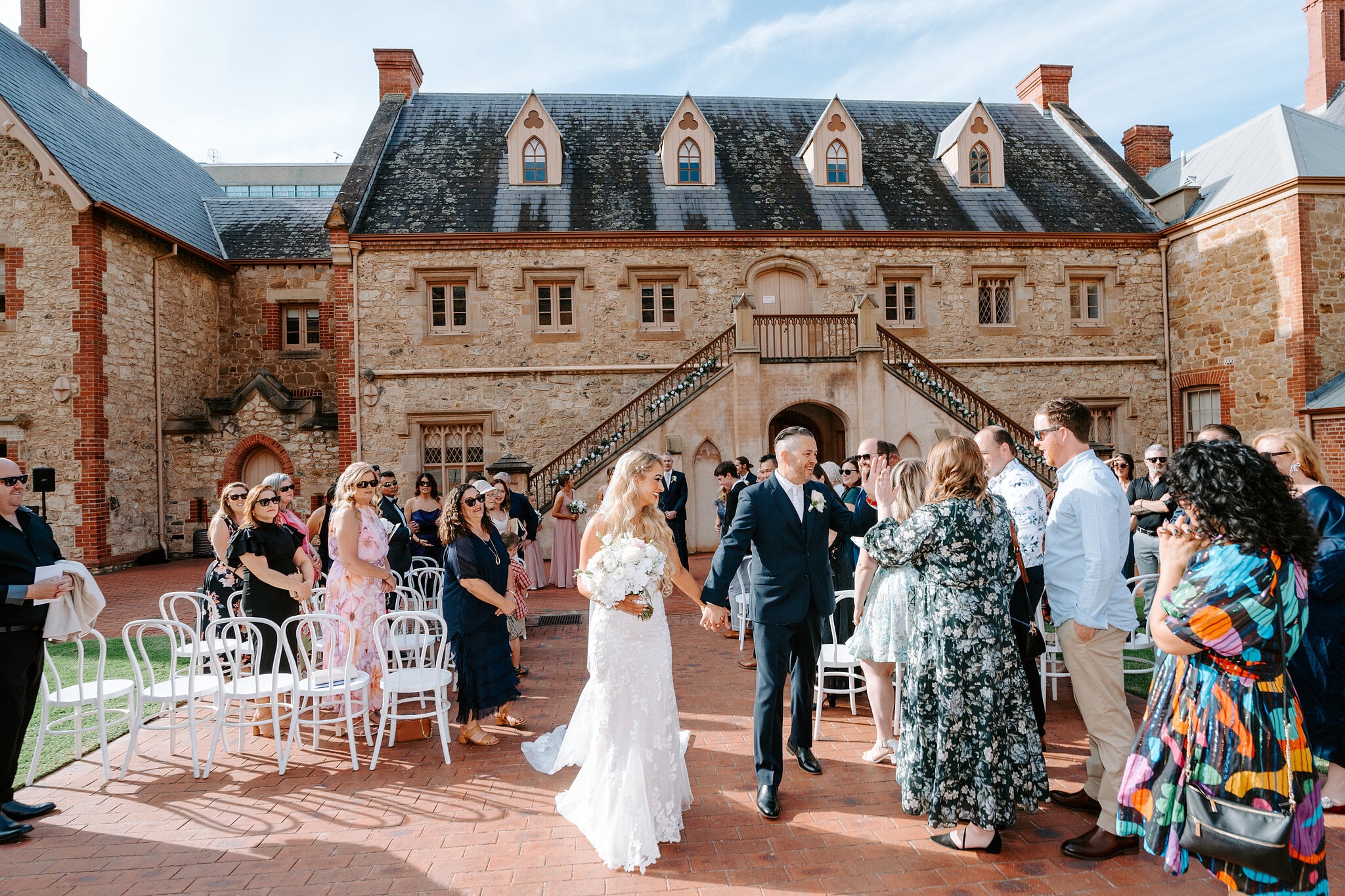 Sarah and Joe walk hand in hand through their cheering guests.