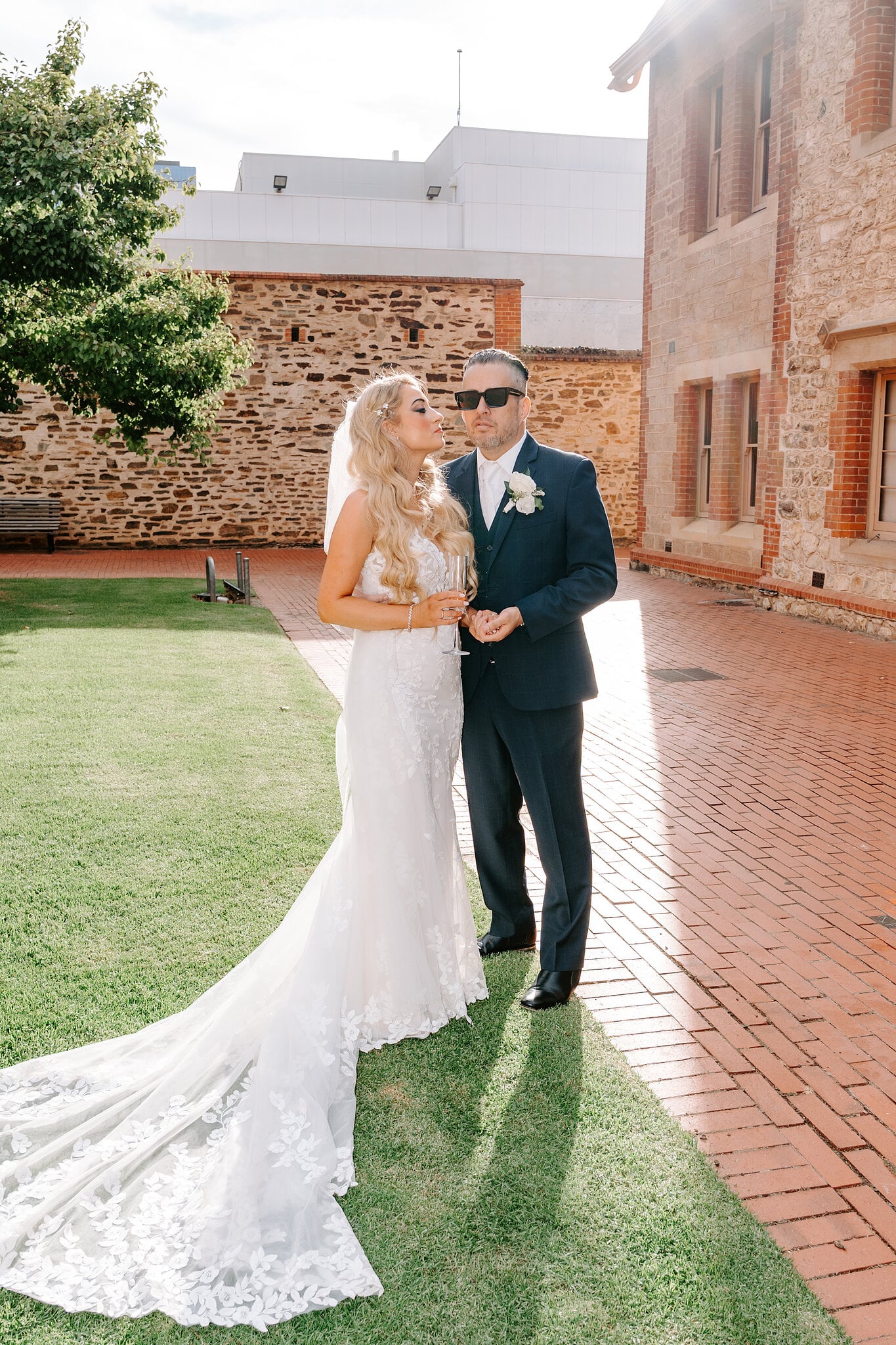 Sarah and Joe stand together on the courtyard lawn, Joe in sunglasses.