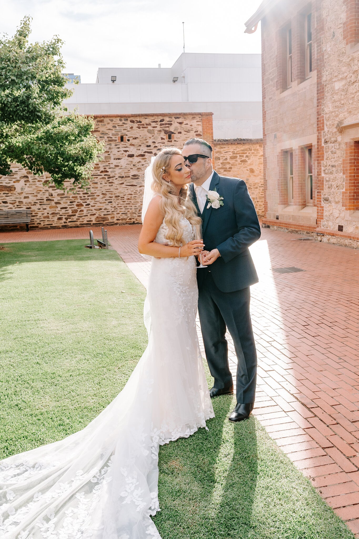 Joe kisses Sarah’s cheek on the lawn beside the old stone wall.