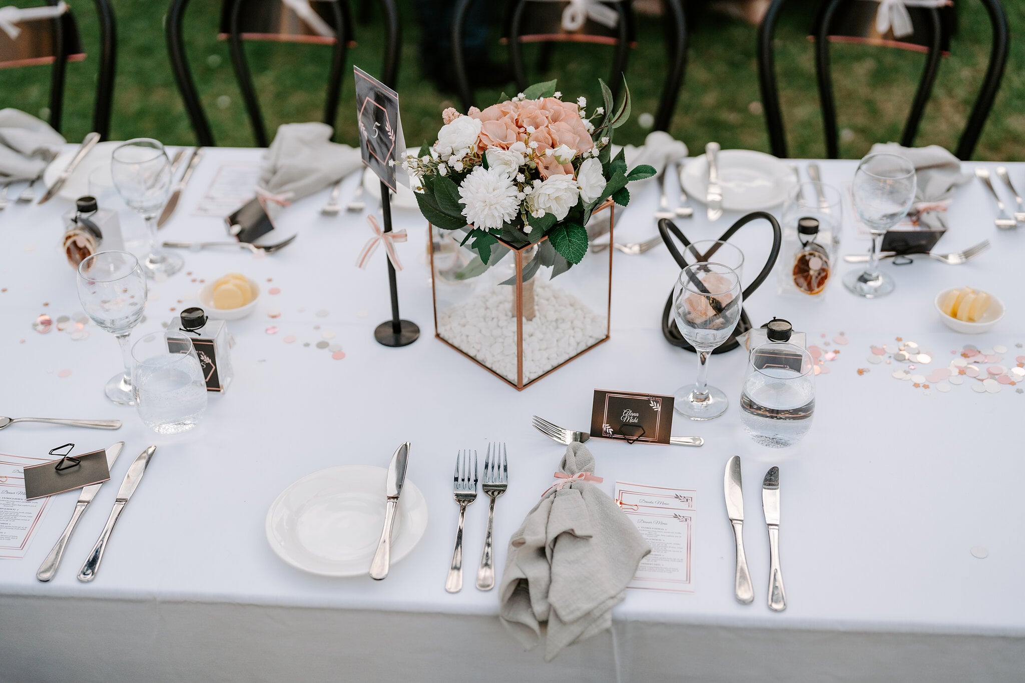 A long reception table with copper-framed glass centrepieces of blush roses and white chrysanthemums.