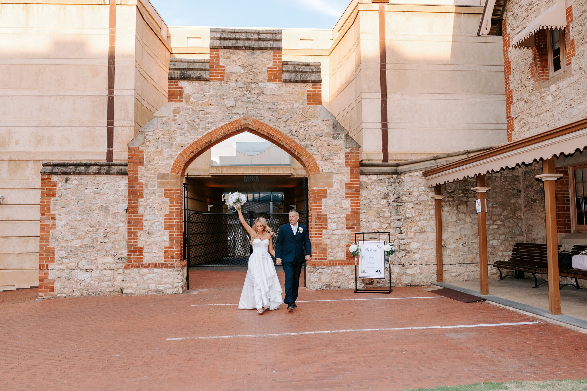 Sarah, in her second dress, and Joe make their entrance through the Gothic stone archway, bouquet raised.