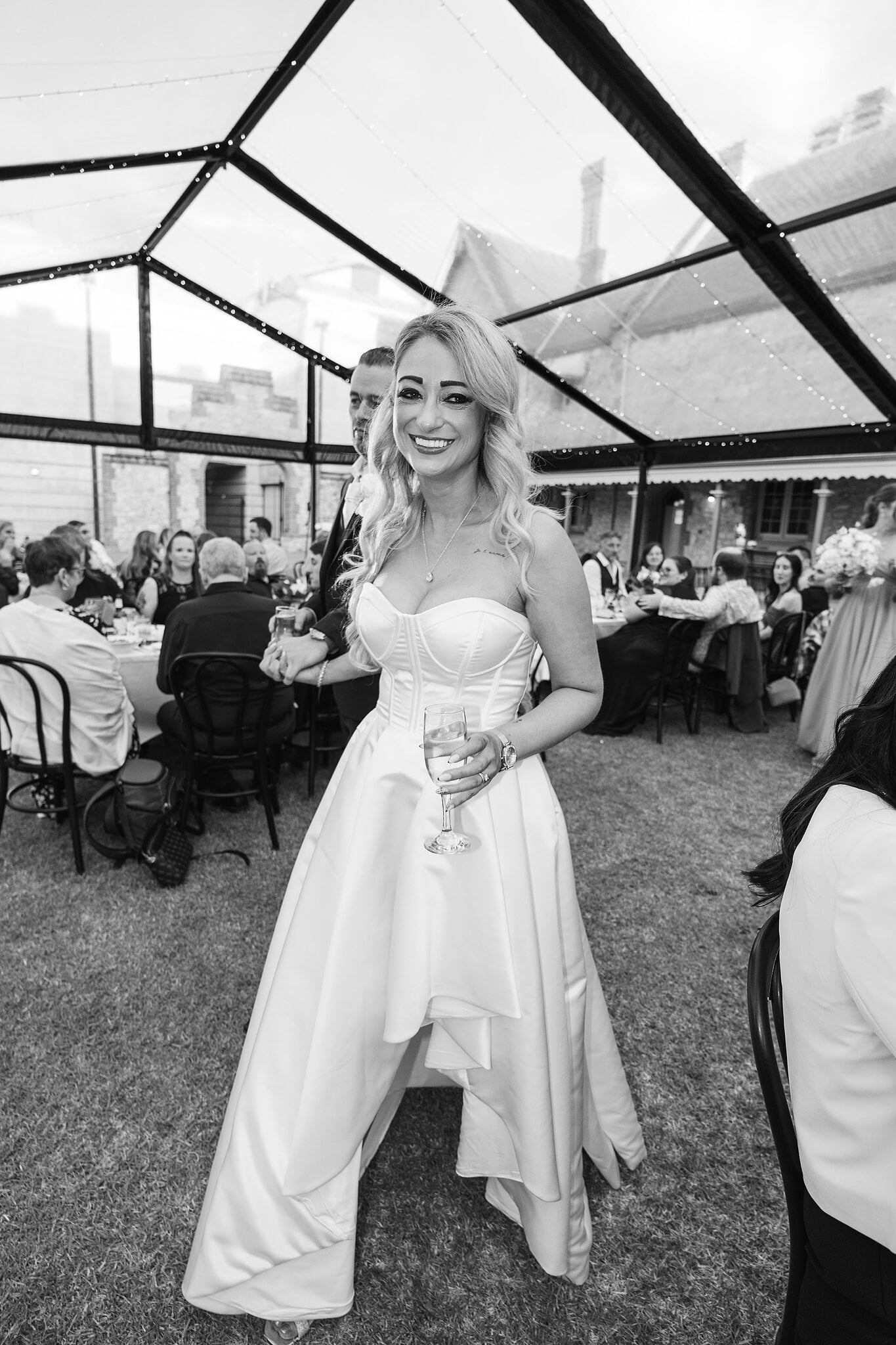 Sarah laughs in her strapless satin gown in the marquee, in black and white.