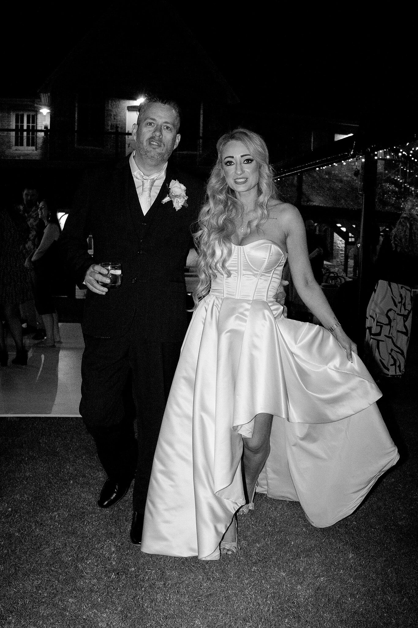 Sarah and Joe walk across the lawn at night, in black and white.