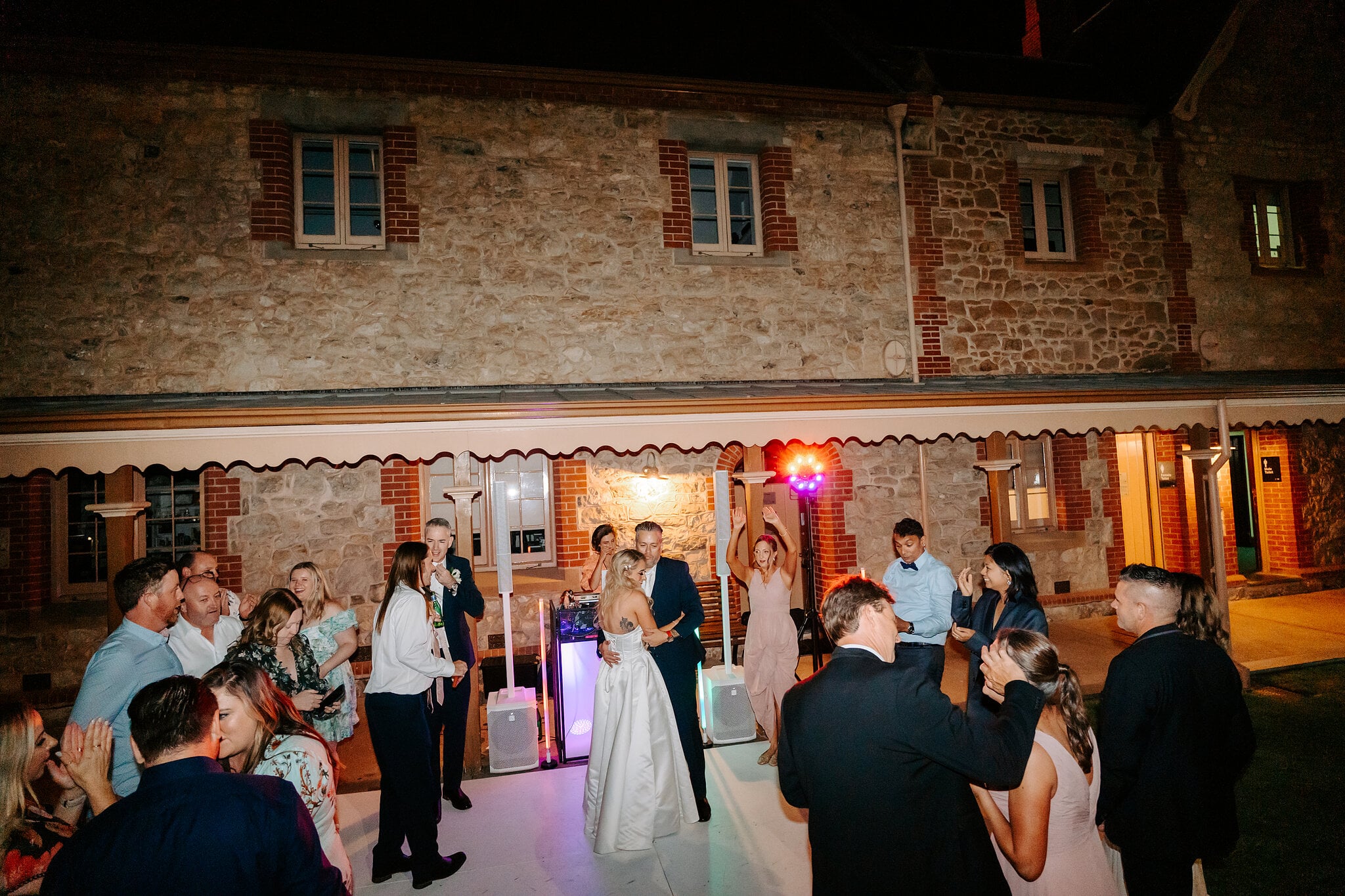 Guests crowd the dance floor under the verandah as Sarah and Joe dance.