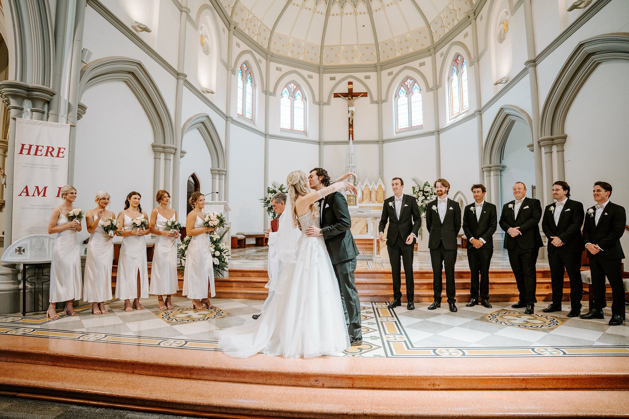 Claire and George kiss at the altar of St Joseph’s Church in Subiaco, bridal party either side.