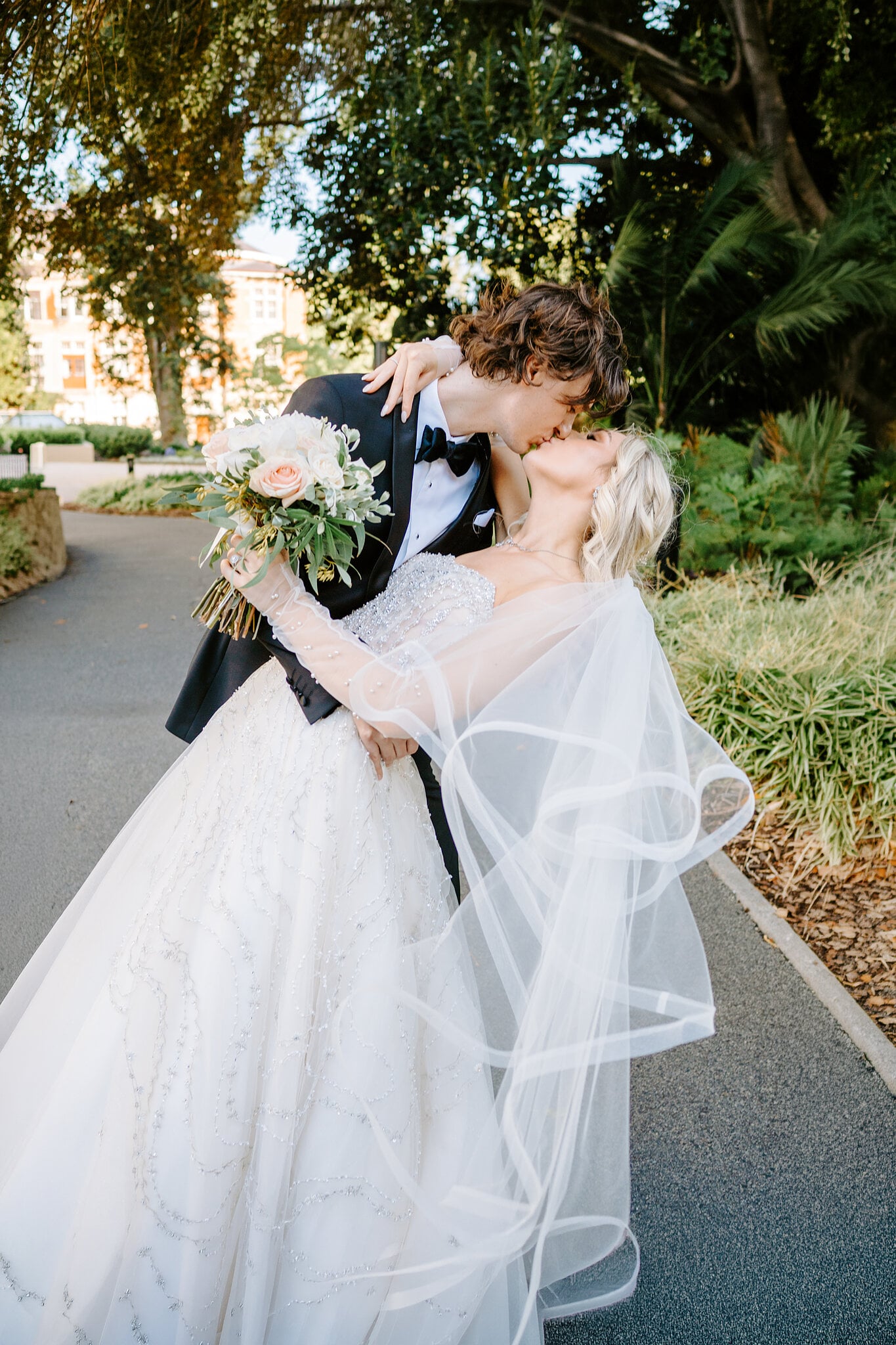 George dips Claire for a kiss in the Supreme Court Gardens, her veil spilling down.