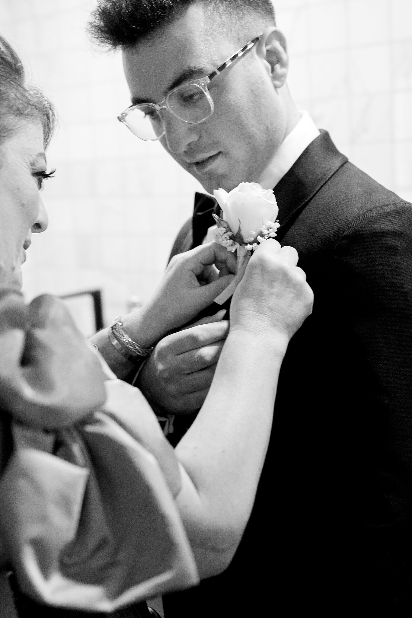 A white rose buttonhole goes onto Jordan’s tuxedo lapel, in black and white.