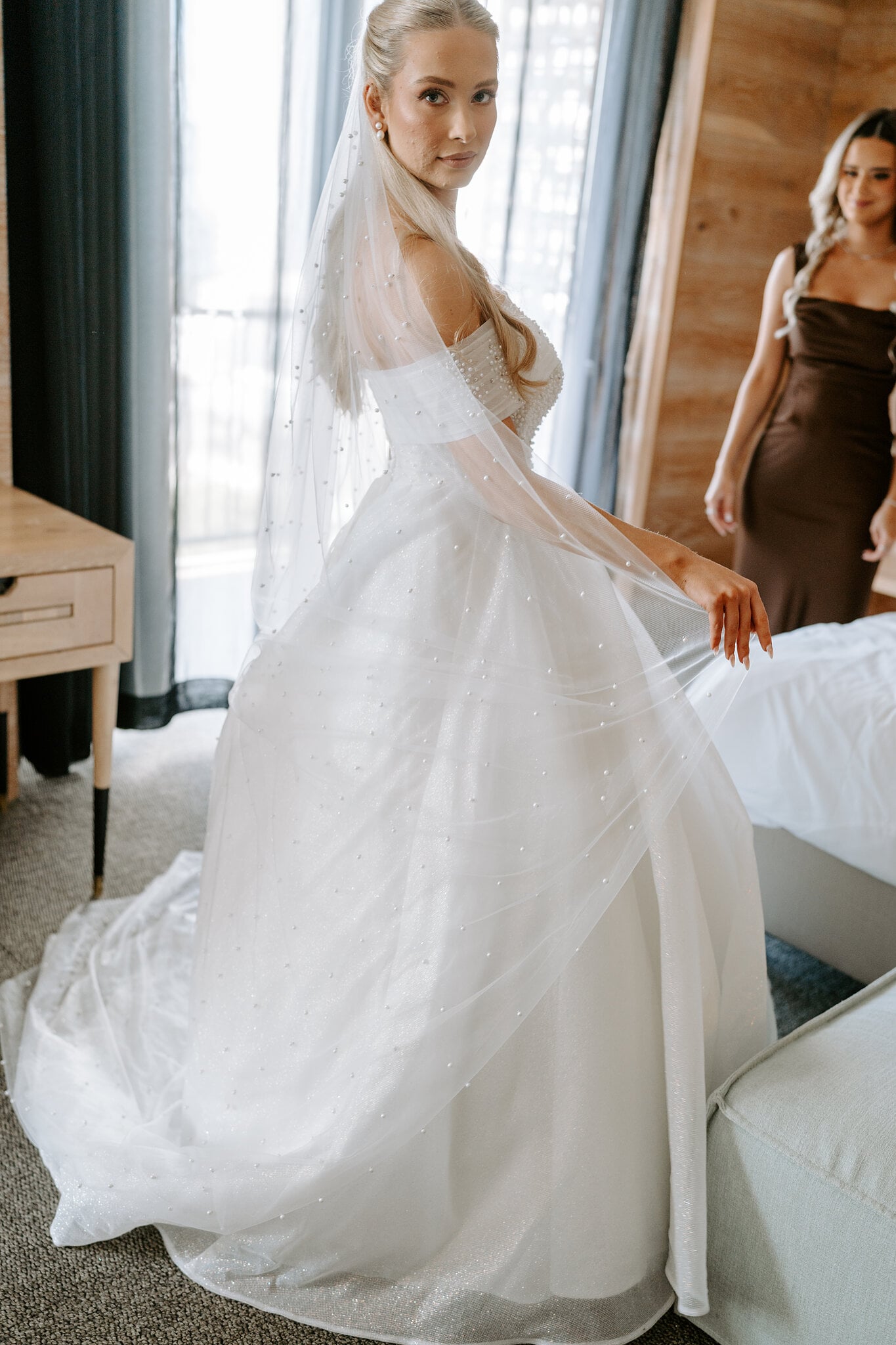 Sorayaa glances over her shoulder, her pearl-scattered veil trailing behind her.