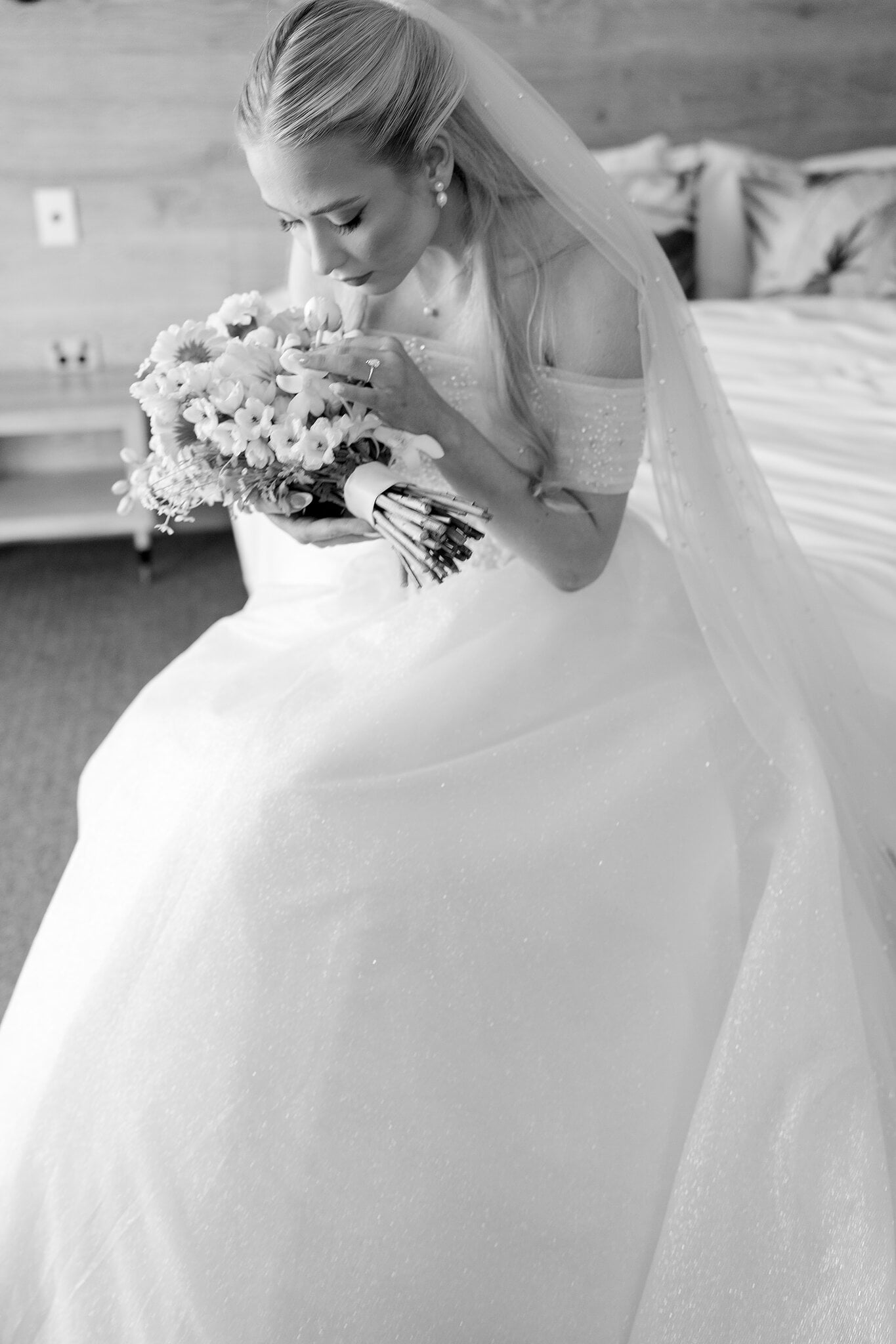 Sorayaa breathes in her bouquet beneath her long veil, in black and white.