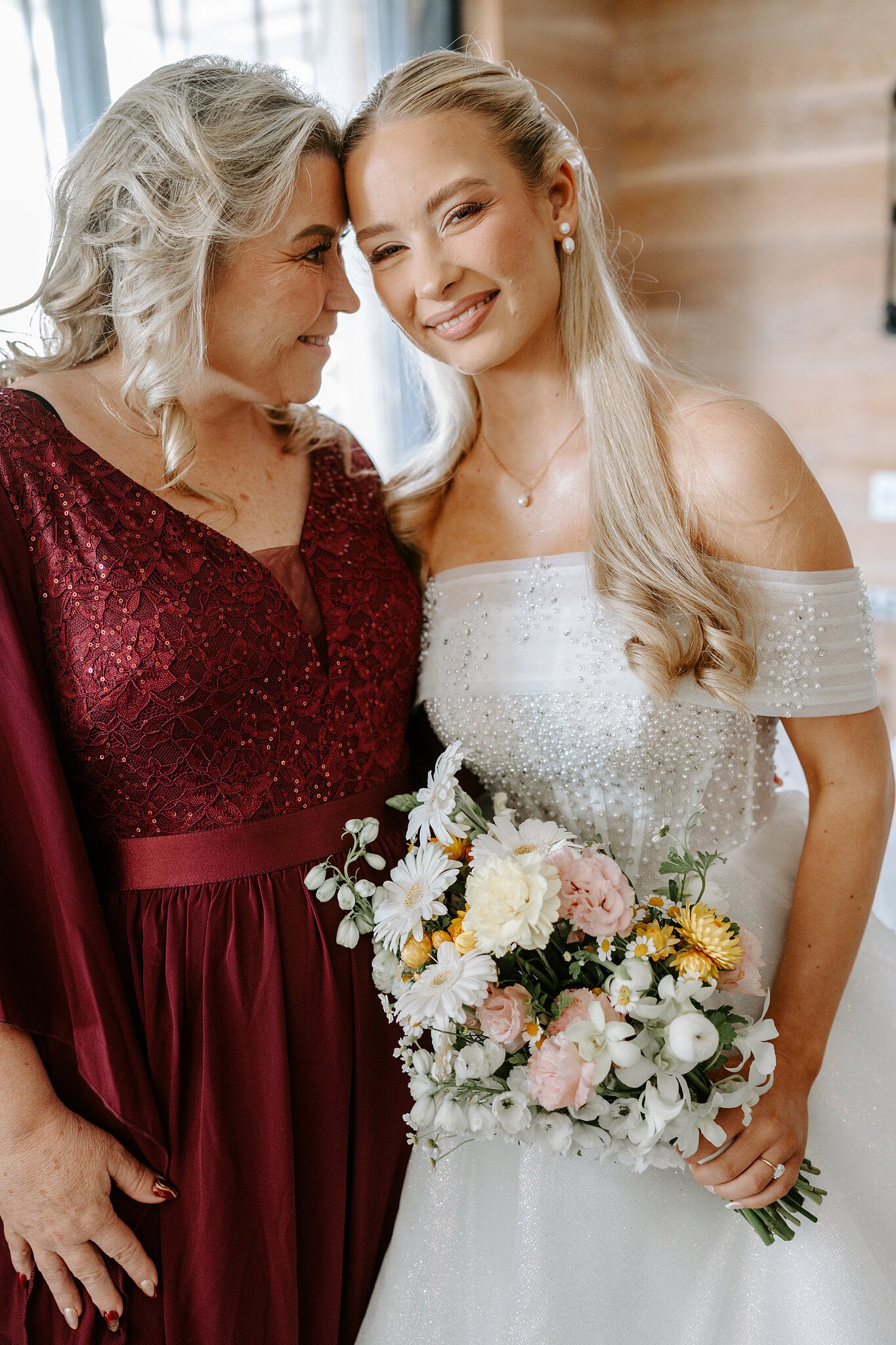 Sorayaa rests her cheek against a loved one in burgundy sequins, her pastel daisy bouquet in hand.
