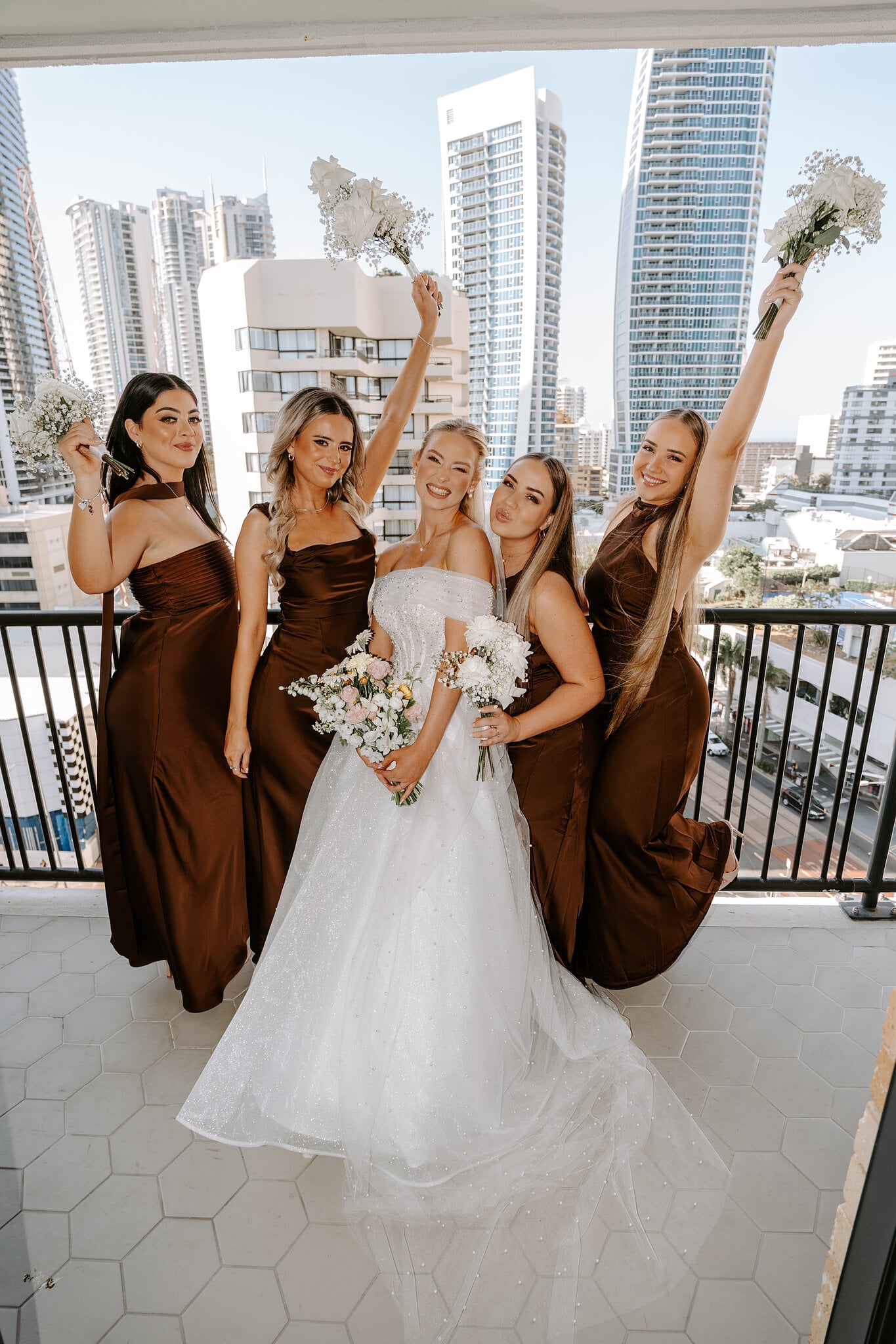 Bouquets in the air as Sorayaa and her bridesmaids celebrate on a balcony above Surfers Paradise.