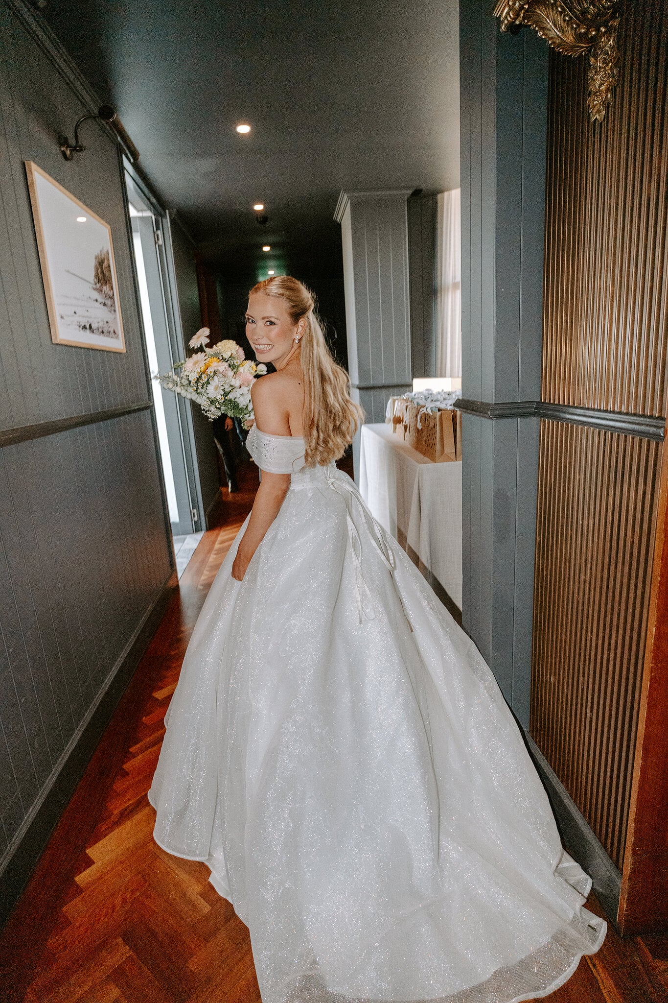 Sorayaa looks back along the panelled hallway, her train spread across the parquet.