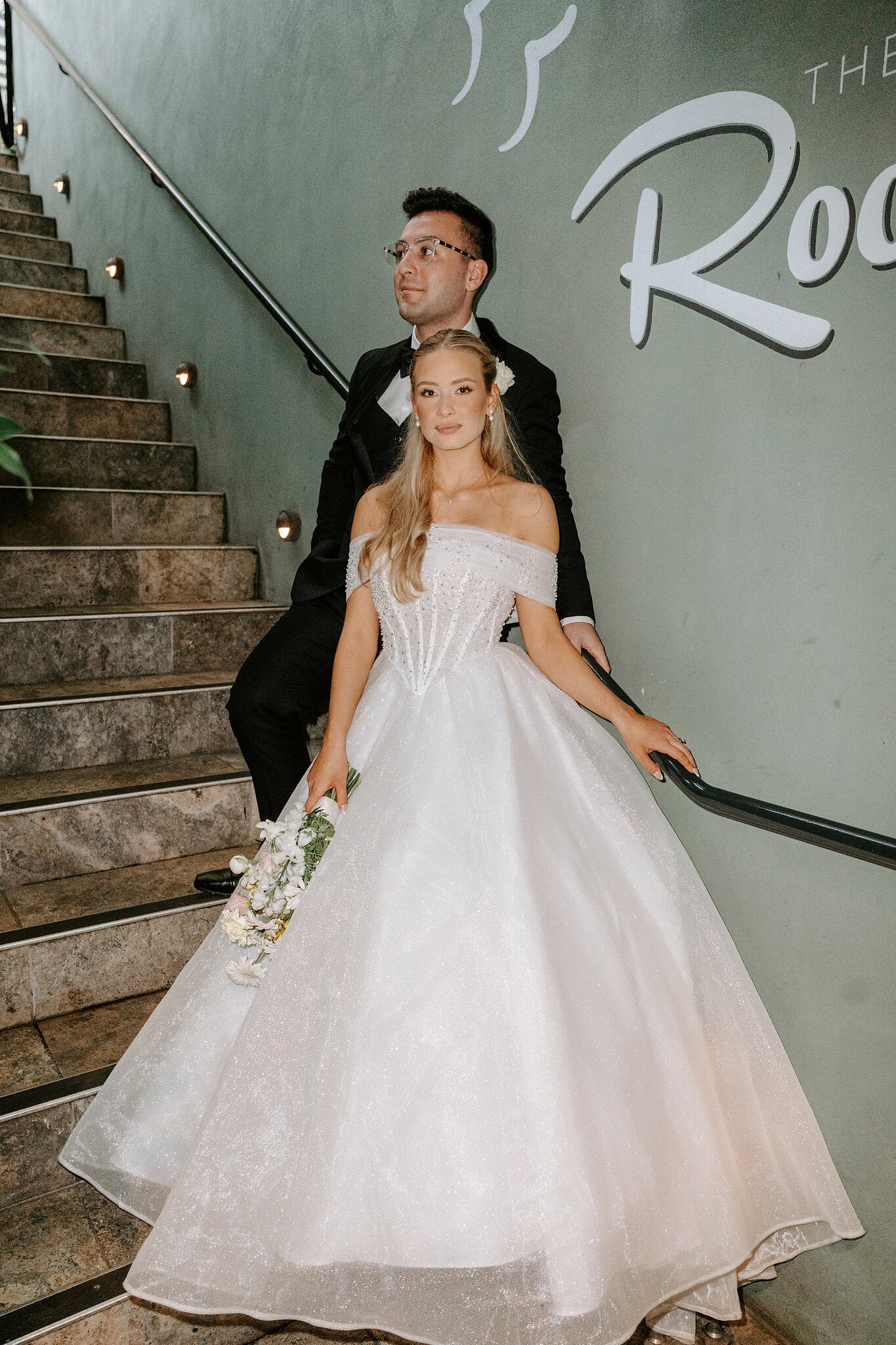 Sorayaa and Jordan on the stairs beneath The Rooftop sign at The Island Gold Coast.