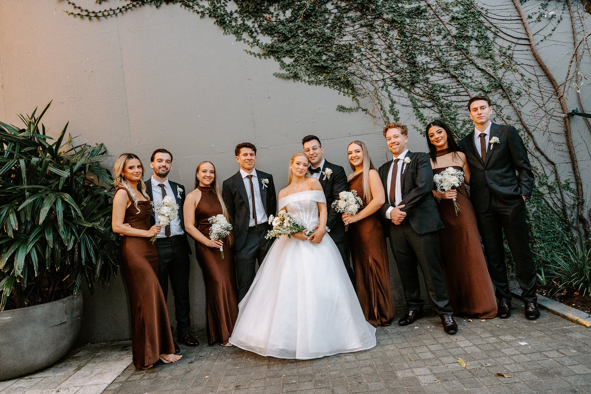 The whole bridal party against an ivy-draped wall at The Island Gold Coast.