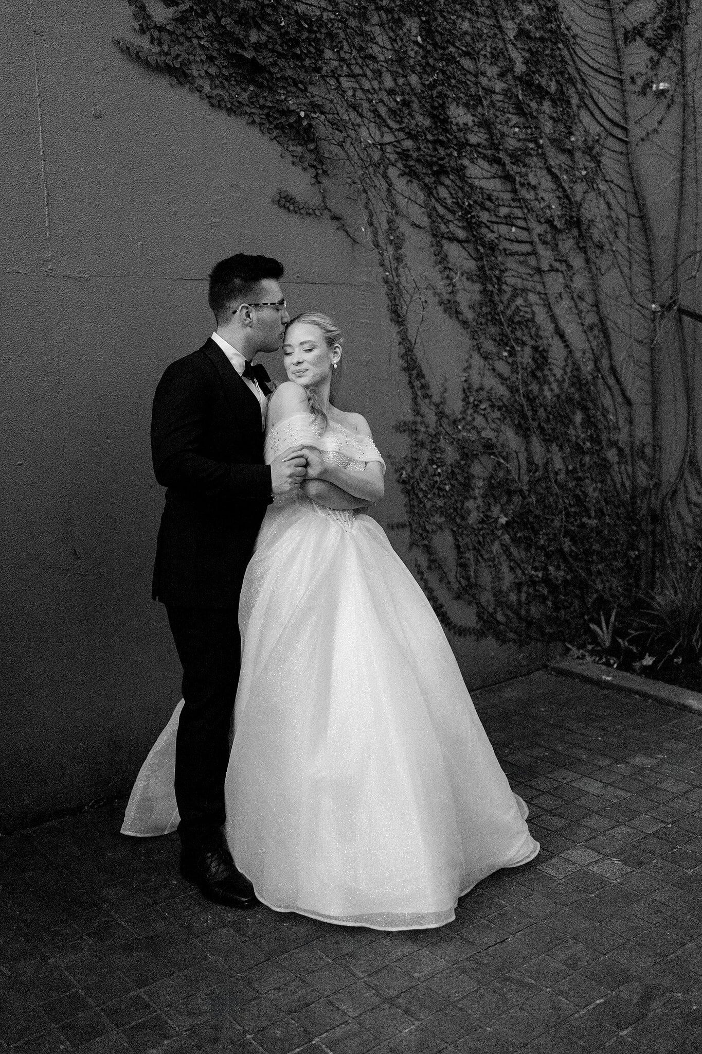 Jordan kisses Sorayaa’s forehead as she closes her eyes, in black and white.