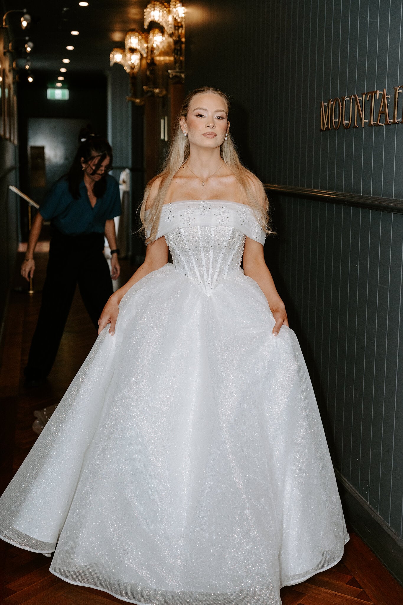 Sorayaa in the dark panelled hallway of The Penthouse, chandelier sconces glowing, moments before the ceremony.