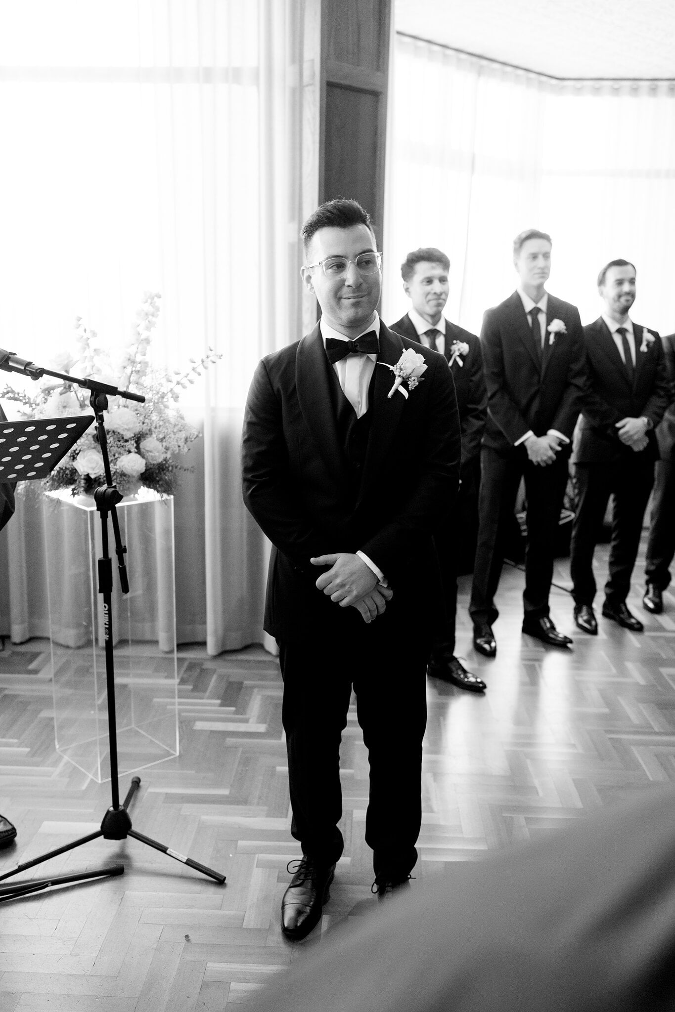Jordan waits at the front of The Penthouse with his groomsmen, in black and white.