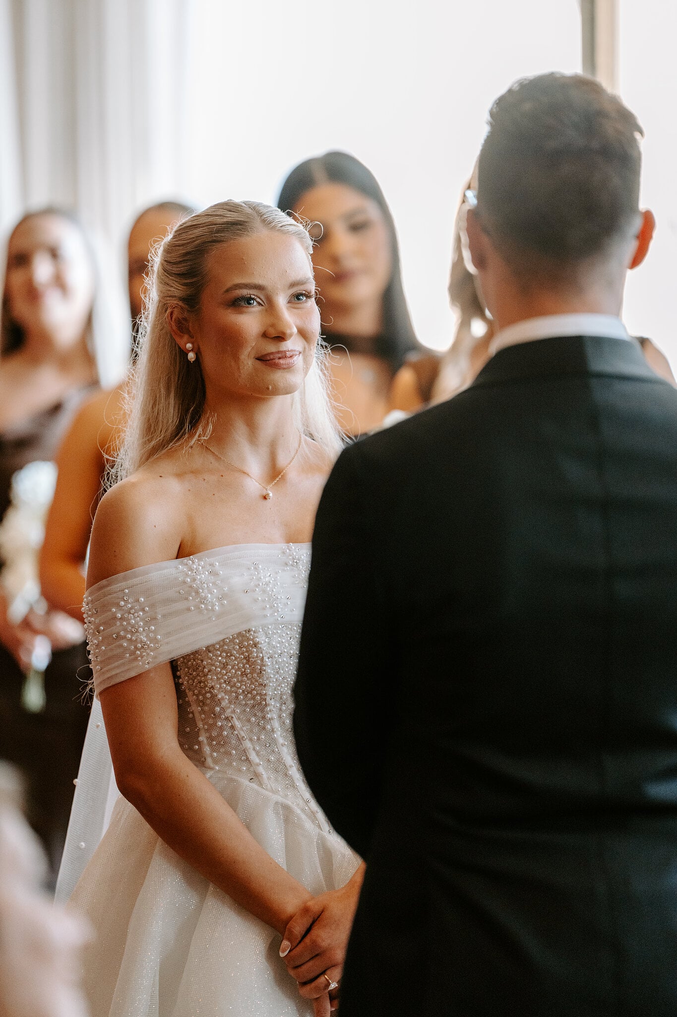 Sorayaa smiles up at Jordan during their vows, her bridesmaids behind her.
