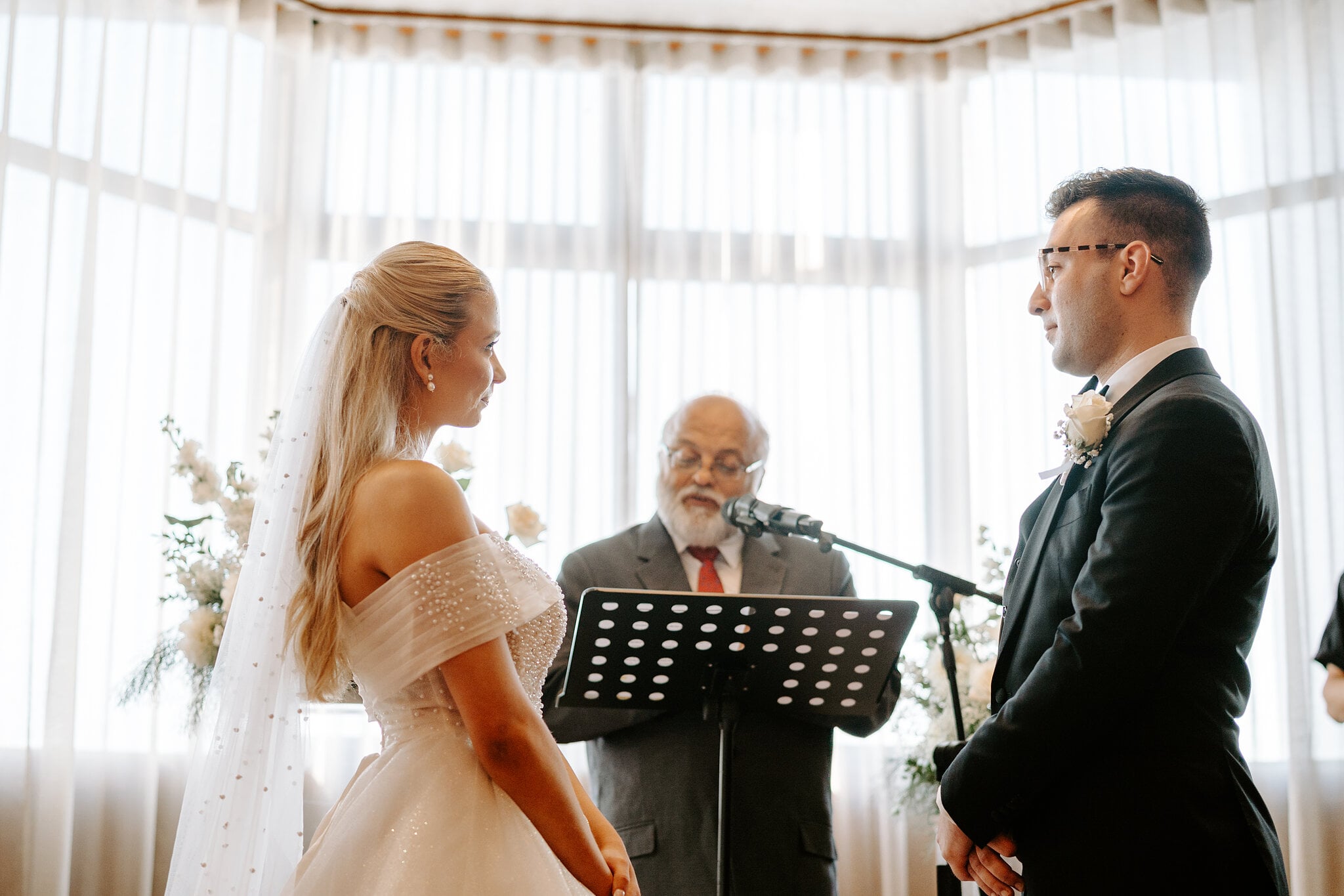 Sorayaa and Jordan face each other before the celebrant against The Penthouse’s curtained windows.