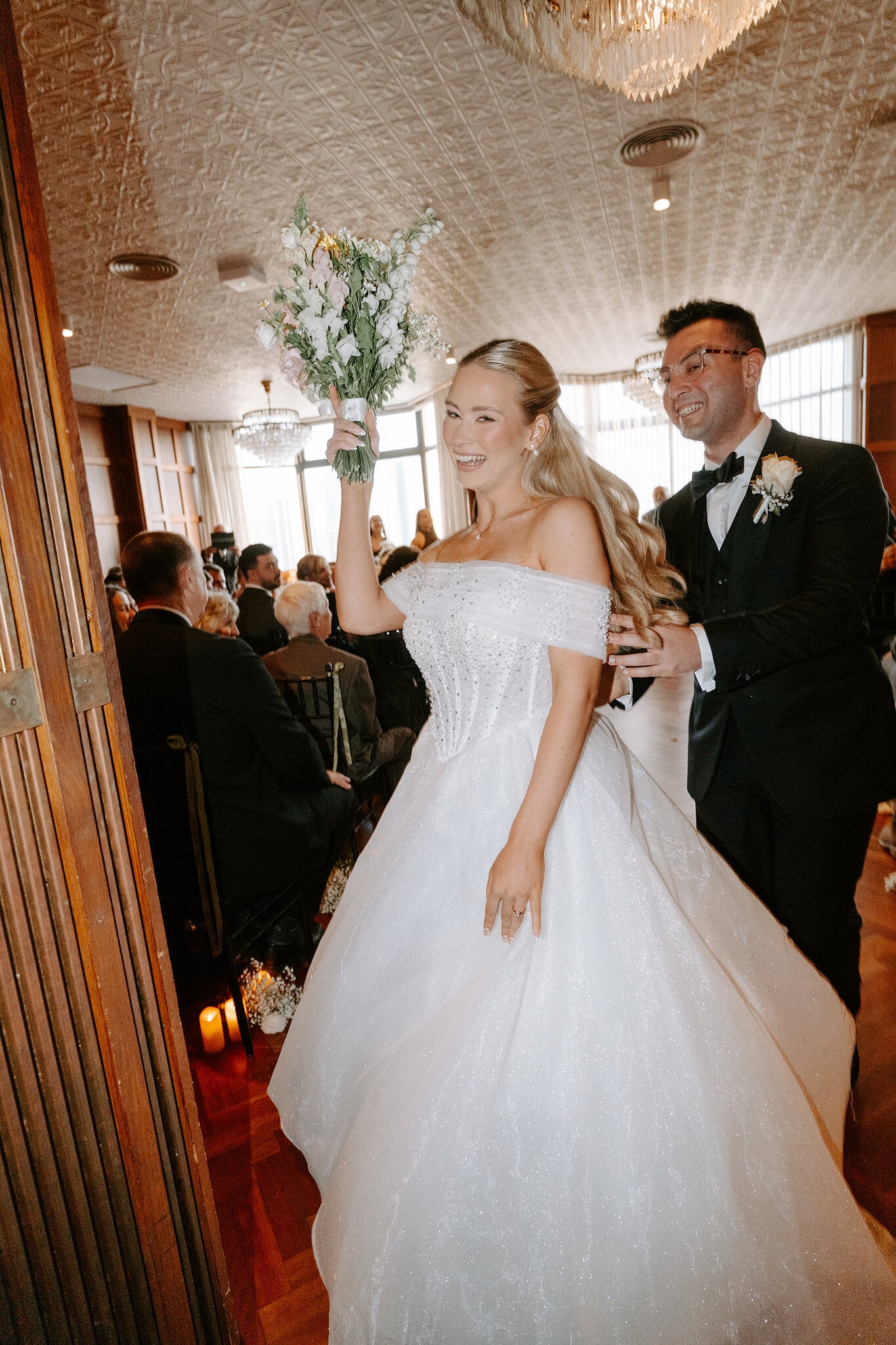 Sorayaa holds her bouquet high on the way back up the aisle with Jordan.